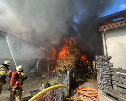 Feuerwehrlöscharbeiten bei Garagenbrand; starke Rauchentwicklung, angrenzendes Wohnhaus gefährdet.