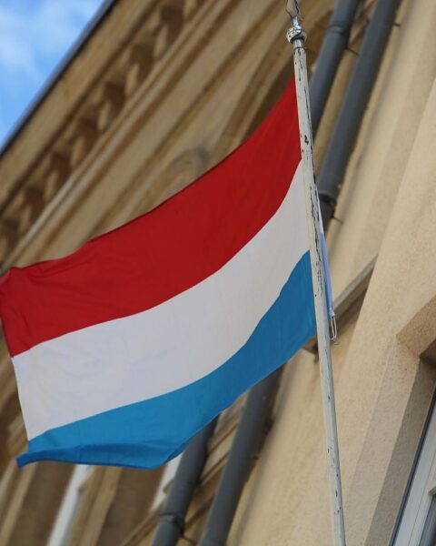 Fahne von Luxemburg im Vordergrund, symbolisch für die rechtswidrige Grenzkontrolle an der Grenze.