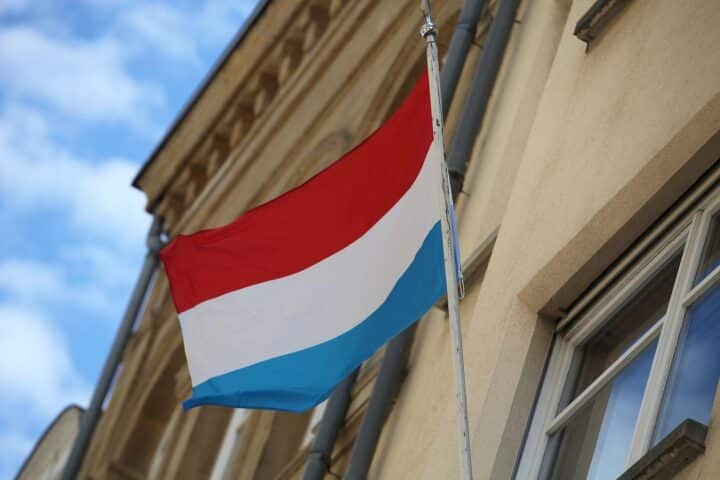 Fahne von Luxemburg im Vordergrund, symbolisch für die rechtswidrige Grenzkontrolle an der Grenze.