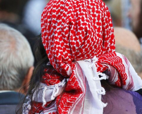 Ein Mann mit Pali-Tuch demonstriert symbolisch vor der Gedenkstätte Buchenwald.