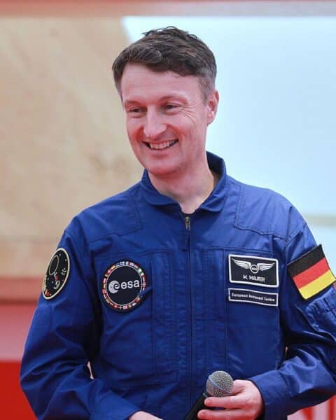 Matthias Maurer mit Raumanzug vor einer Mondlandschaft; symbolisiert Deutschlands Mondmission.