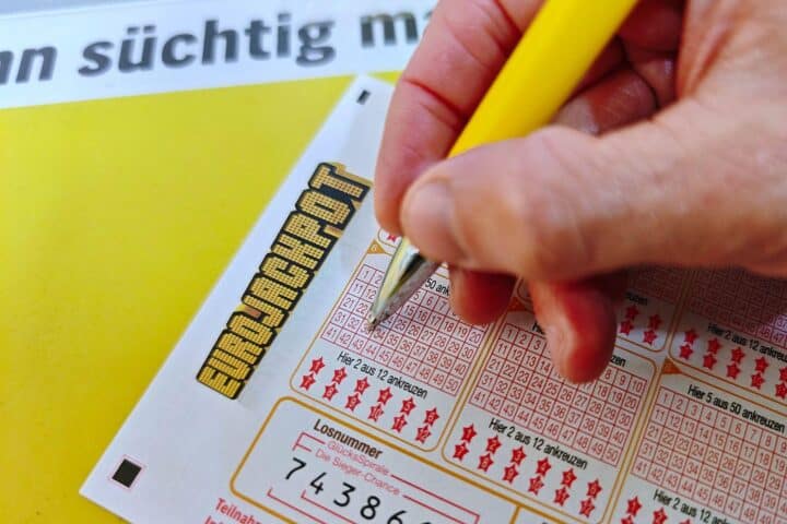 Ein Eurojackpot-Spielschein mit Gewinnzahlen und symbolischen Eurozeichen im Hintergrund.
