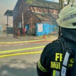 Großbrand mit Rauchsäule, Feuerwehr im Einsatz, brennende Altpapierballen, Verletzter, dramatische Szene.