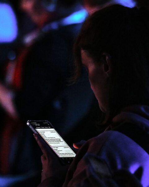 Junge Frau interagiert mit Smartphone, symbolisiert Herausforderungen und Regeln für digitale Sicherheit.