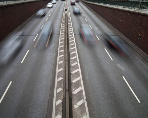 Verkehrsszene mit Fahrzeugen, Fokus auf Sicherheit, Tempo 30-Schilder und Menschen im Straßenverkehr.