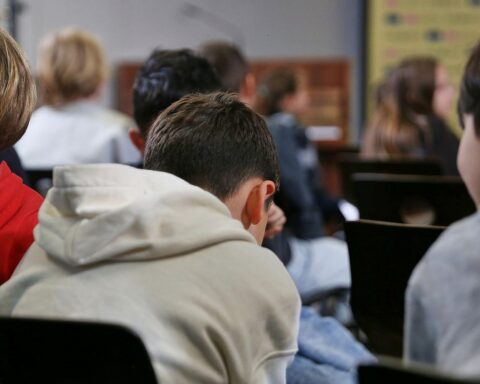 Kinder in einer Schulklasse, Lehrer erklärt, bunte Schulmaterialien, Vorfreude auf neues Schuljahr.