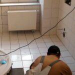 Fliesenleger bei der Arbeit, symbolisiert handwerkliche Leistung und aktuelle wirtschaftliche Herausforderungen im Handwerk.