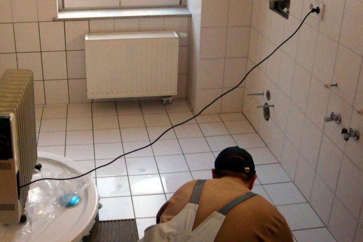 Fliesenleger bei der Arbeit, symbolisiert handwerkliche Leistung und aktuelle wirtschaftliche Herausforderungen im Handwerk.