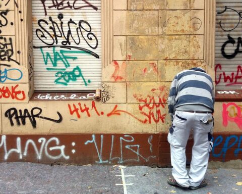 Graffiti-Entfernung an einer Wand, Symbol für Handwerk und praktische Tätigkeit im Beruf.