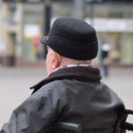 Gewerkschaftschefin kritisiert Rentenkürzungen, protestbereite Beschäftigte, Mann im Rollstuhl symbolisiert Zugänglichkeit.