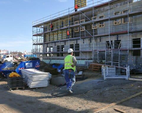 Bauarbeiter auf Baustelle, Sorgen über steigende Zinsen und sich verbessernde Auftragslage im Wohnungsbau.
