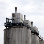 Industrieanlage mit Maschinen, die Investitionen symbolisieren; aufsteigende Kurven und positive Erwartungen darstellen.