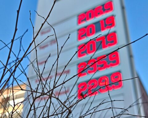 Tankstelle mit Preistafel, gestiegene Kraftstoffpreise durch Inflation und geopolitische Ereignisse hervorhebend.