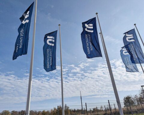 Fahnen der Jungen Union im Kontext von Gesundheitskosten und sozialer Gerechtigkeit in Deutschland.