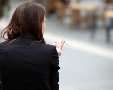 Frau raucht, Zigarettenpackung sichtbar; symbolisiert Diskussion über höhere Tabaksteuern zur Entlastung des Gesundheitssystems.