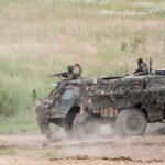 Ein moderner Panzer, der in der Produktion ist, mit Teammitgliedern in einer Fabrik.