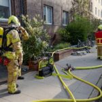 Kellerbrand in Mehrfamilienhaus, Feuerwehr im Einsatz, verletzte Personen, Rauch und Einsatzkräfte sichtbar.