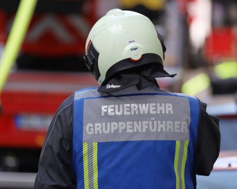 Feuerwehrleute bekämpfen Kellerbrand in Mehrfamilienhaus, Rettungsdienst versorgt verletzte Person.
