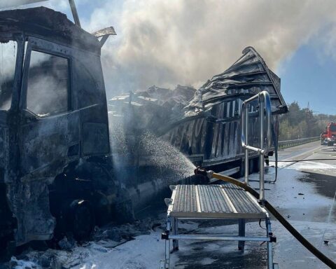 Ein brennender LKW mit Feuerwehr im Einsatz und einem LNG-Tank zur Kühlung.