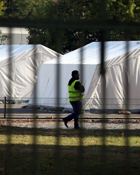 Flüchtling und Sicherheitsmann in einer Zeltstadt, Symbol für Integration und Unterstützung.