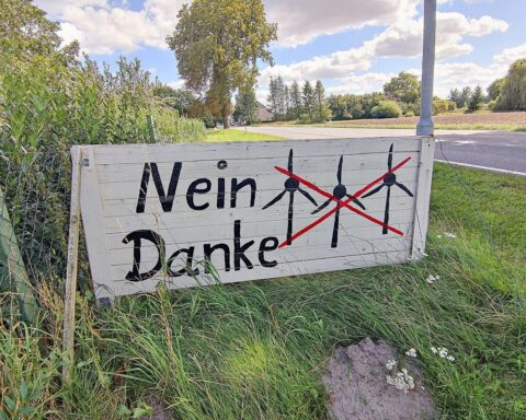 Protest gegen Windräder: Menschen halten Schilder, fordern Veränderungen in der Energiepolitik.