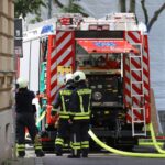 Feuerwehr beim Löschen eines Wohnungsbrandes, Rettung eines verletzten Mannes. Einsatzkräfte arbeiten intensiv.