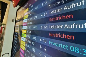 Flughafen mit gesperrten Abflug-Anzeigen und wartenden Passagieren wegen Pilotenstreiks bei Lufthansa.