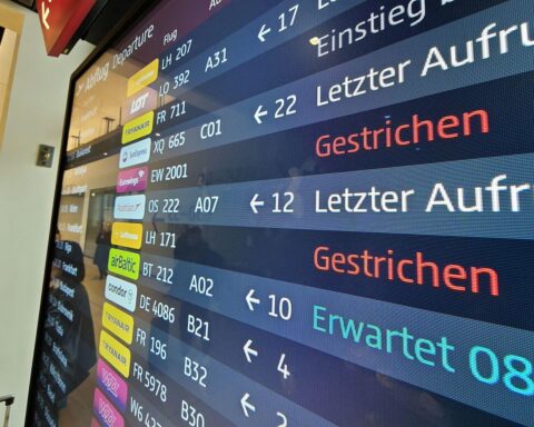 Flughafen mit gesperrten Abflug-Anzeigen und wartenden Passagieren wegen Pilotenstreiks bei Lufthansa.