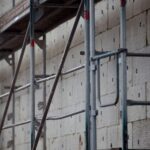 Gerüstbau für Wärmedämmung mit Bauarbeiten im Hintergrund und Investoreninteresse im Fokus.