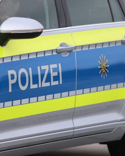 Maskiertes Überfall-Opfer vor Getränkemarkt, Polizei und Rettungskräfte im Einsatz.