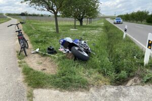 Motorradunfall auf Straße, Pedelec und Motorradfahrer betroffen, Polizei sucht Zeugen.