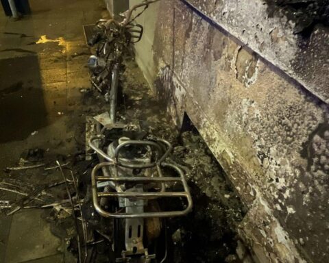 Abgebrannter Motorroller vor einem Mehrfamilienhaus, von der Polizei dokumentiert. Ermittlungen laufen.