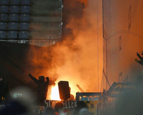 Fans zünden Pyrotechnik im Stadion, symbolisieren damit die Spannungen und Konflikte im Fußball.