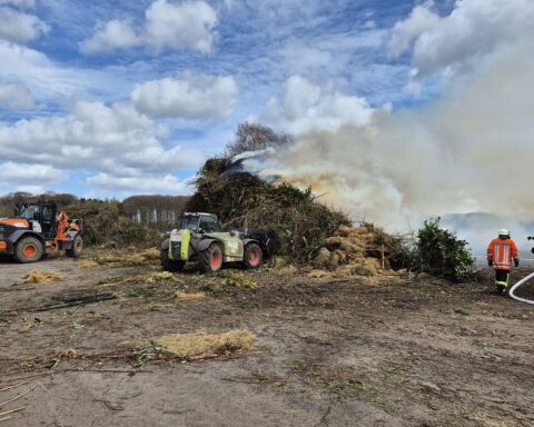Ein größeres Osterfeuer, das in Brand geraten ist, mit Feuerwehr und Löschfahrzeugen im Einsatz.