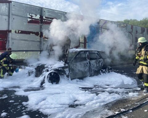 Auto in Flammen, Feuerwehr im Einsatz, dichte Rauchentwicklung, Rettungsgasse auf Autobahn sichtbar.