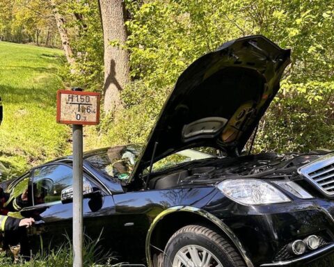 Einsatzkräfte der Feuerwehr sichern Unfallfahrzeug im Straßengraben, Person wird befreit.