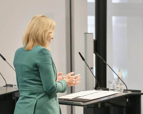 Nina Warken diskutiert Gesundheitsreform, umgeben von politischen Beratern und kritischen Stimmen.