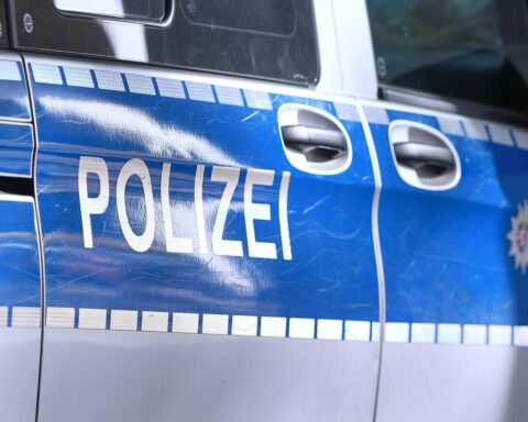 Polizisten stehen neben einem Wertstoffhof, während tatverdächtige Männer abgeführt werden.
