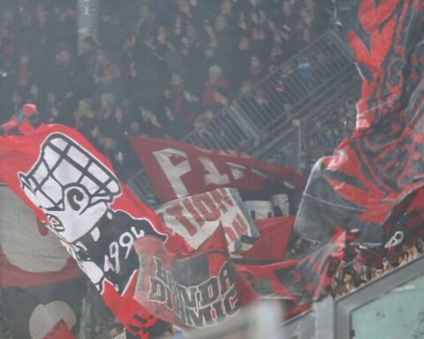 Fans des 1. FC Nürnberg marschieren zum Stadion, Pyrotechnik und Polizeipräsenz erkennbar.