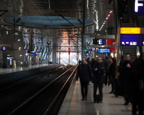 Reisende in einer Bahnhalle, Diskussion über Schwarzfahren und dessen rechtliche Konsequenzen.