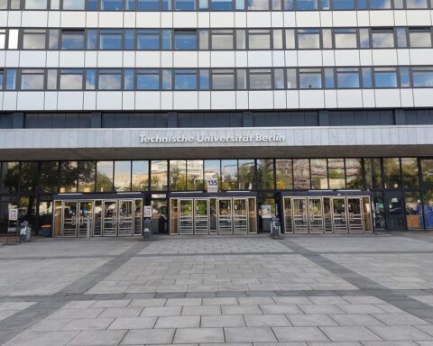 Ein stark beschädigter Hörsaal mit Eimern, Flatterband und einem defekten Dach.