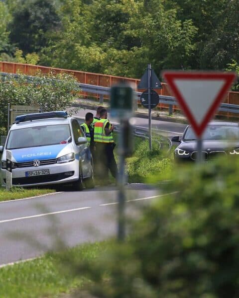 Verkehrskontrolle an der deutschen Grenze, Beamte im Einsatz, potenzielle Sicherheitsmaßnahmen sichtbar.