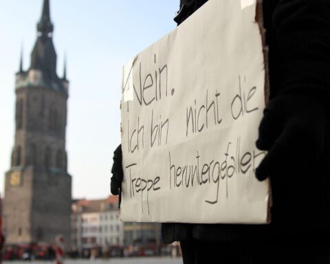 Demonstrantin hält Banner gegen Gewalt an Frauen bei staatlicher Unterstützung für Gewalthilfegesetz.