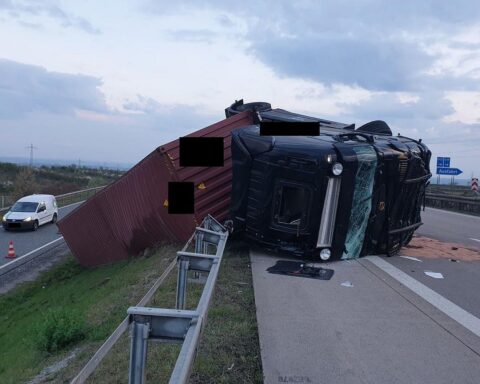Sattelzug liegt umgekippt auf der Autobahn, Schutzleitplanke durchbrochen, Verkehr gesperrt.