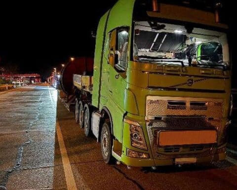 Überladener Schwertransporter mit Kabeltrommel und Stahlseil auf Autobahn Rastanlage.