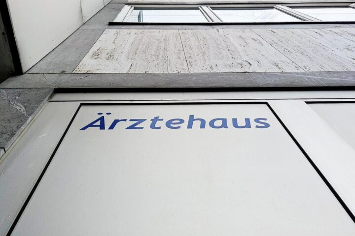 Ärztehaus mit Menschen, Symbol für Gesundheitsversorgung und Kritik an Kürzungen im Gesundheitssystem.