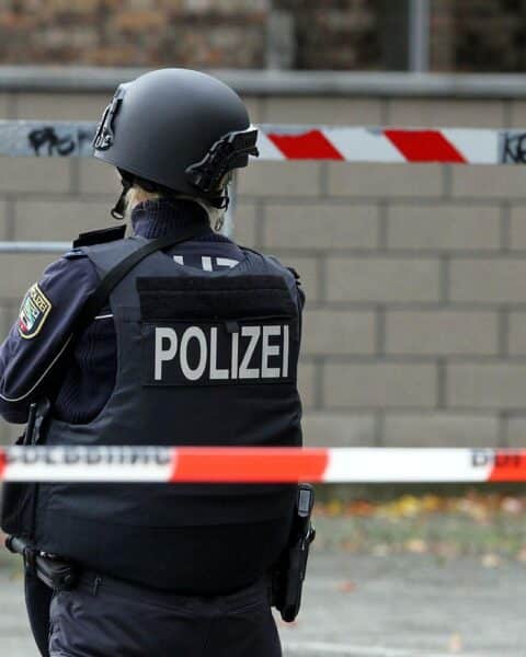 Polizistin hinter Absperrband am Tatort mit Patronen und leeren Hülsen in Berlin.