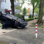 Verunfallter Pkw auf dem Dach, Polizei und Feuerwehr vor Ort, Unfallstelle in Mönchengladbach.