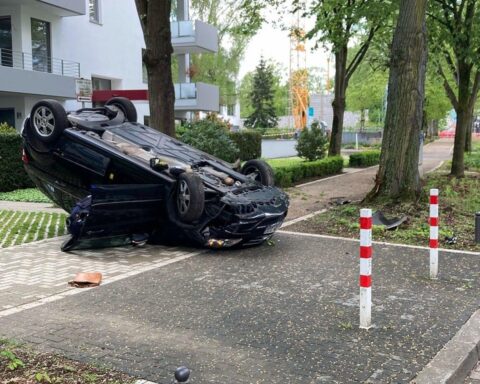 Verunfallter Pkw auf dem Dach, Polizei und Feuerwehr vor Ort, Unfallstelle in Mönchengladbach.