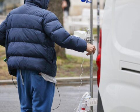 Patient mit Infusionsständer; Symbol für die Auswirkungen von Gesundheitsreformen auf Versicherte.